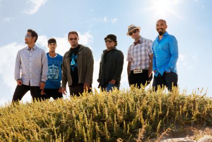 Ozomatli band standing in green field