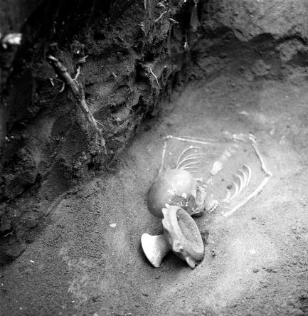 A female skeleton in situ with a ceramic pedestal bowl