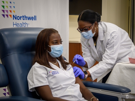 Woman wearing mask receives vaccine shot from doctor