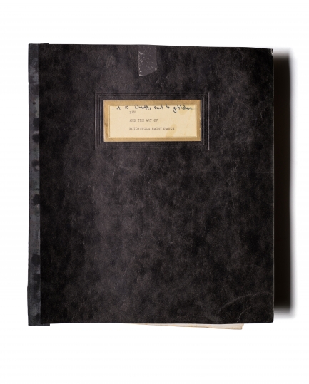 Black, soft-covered book with tan, hand-written label on the cover.