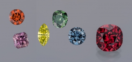 Six singular diamonds in various rainbow colors and cut styles against plain gray background.