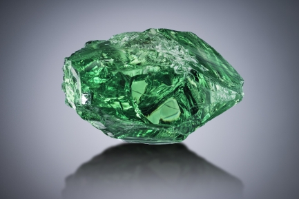 Uncut green gem on neutral gray background