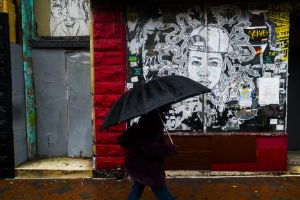 Person on city street with black umbrella