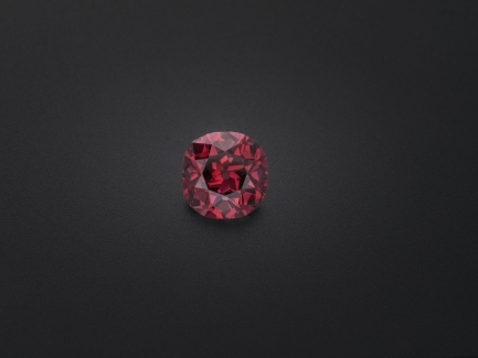 Close-up of a round red diamond against a dark gray background.