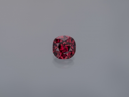 Close-up of a singular red diamong against a light gray background.