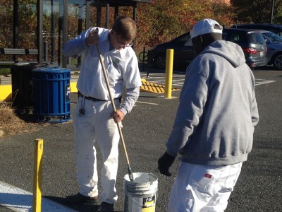 Two men standing with one holding a paint roller in a bucket