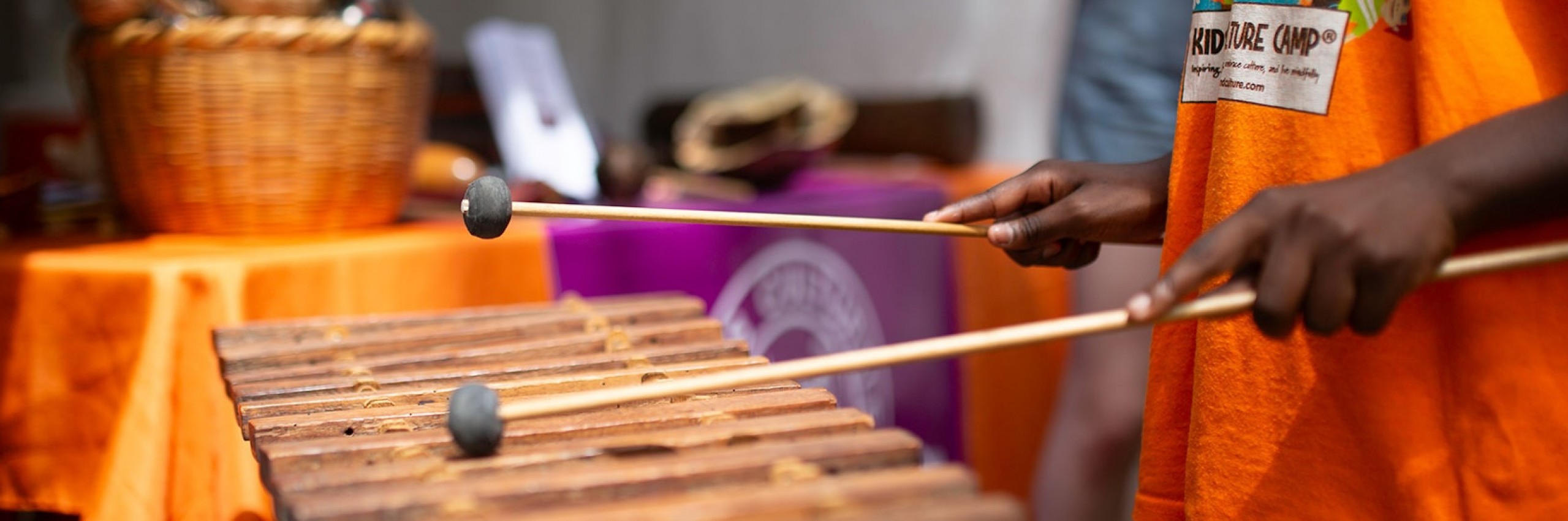 Hands from a young person hold drumsticks.