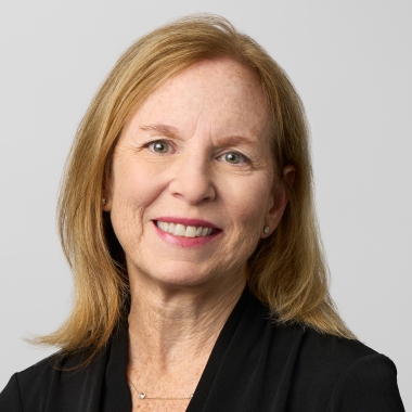 Woman with shoulder length blonde hair in a short sleeve black blouse smiles for a headshot.